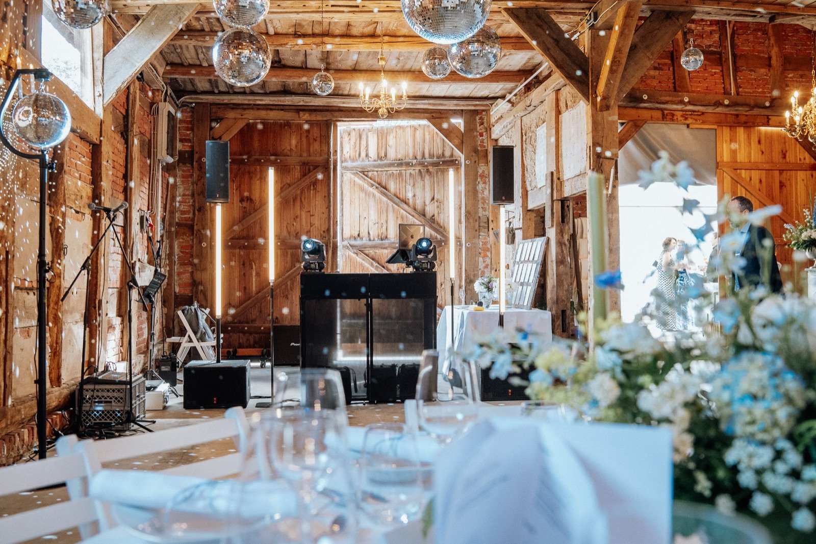 DJ-Setup mit Discokugeln in einer festlich beleuchteten Scheune