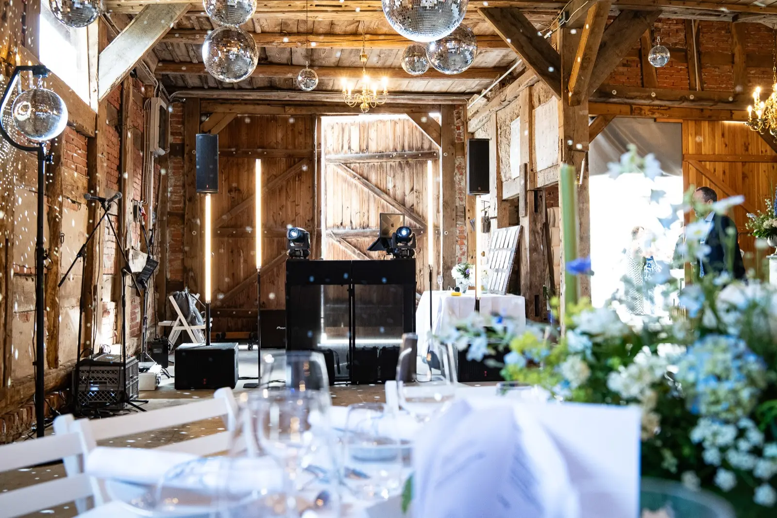 DJ-Setup mit Discokugeln in einer festlich beleuchteten Scheune